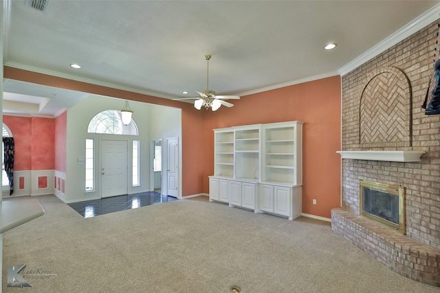 unfurnished living room featuring crown molding, a brick fireplace, ceiling fan, and carpet flooring