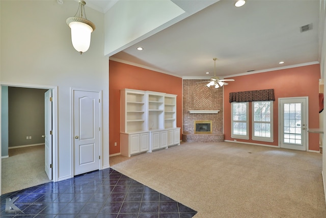 unfurnished living room with ceiling fan, dark colored carpet, crown molding, and a brick fireplace