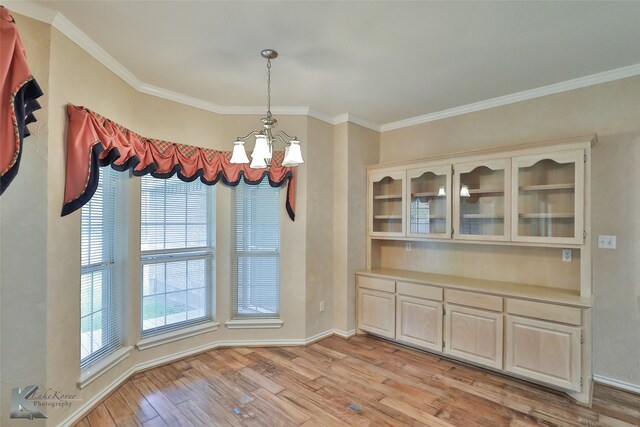 unfurnished dining area featuring a chandelier, light hardwood / wood-style floors, and crown molding