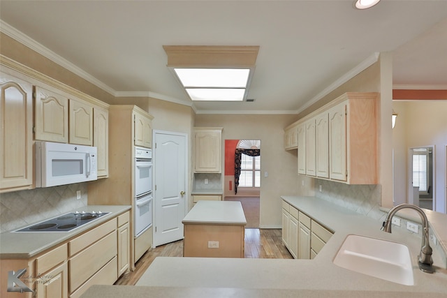 kitchen featuring ornamental molding, white appliances, a kitchen island, sink, and light hardwood / wood-style floors