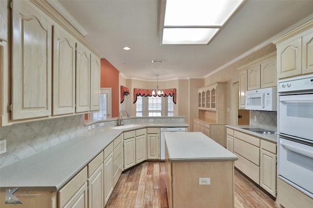 kitchen with white appliances, light hardwood / wood-style flooring, a kitchen island, kitchen peninsula, and sink