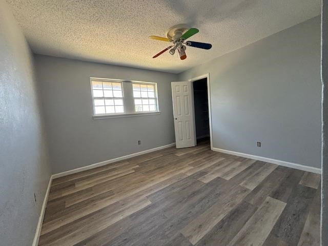 unfurnished bedroom with a textured ceiling, ceiling fan, and dark wood-type flooring