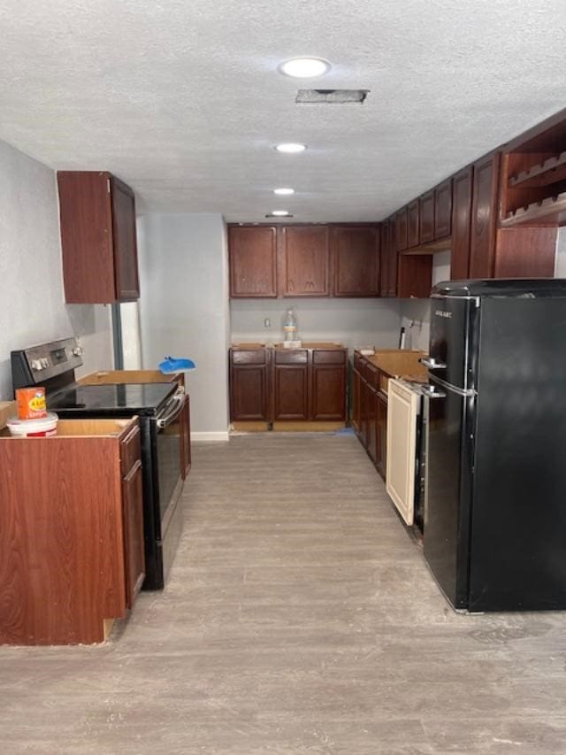 kitchen featuring black appliances, light hardwood / wood-style floors, and a textured ceiling