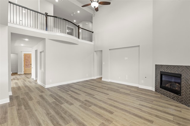4100 Pond Cypress St, Aubrey, TX 76227 - unfurnished living room with ceiling fan, high vaulted ceiling, a tiled fireplace, recessed lighting, and wood finished floors