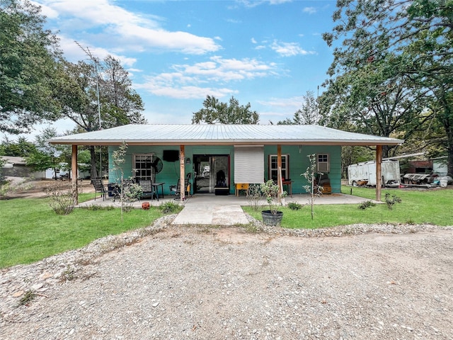 view of front facade with metal roof, driveway, a front lawn, and covered porch