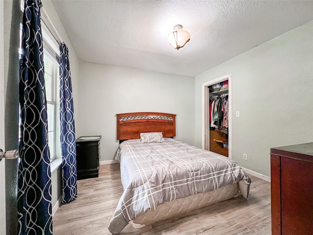 bedroom featuring a textured ceiling, baseboards, and wood finished floors