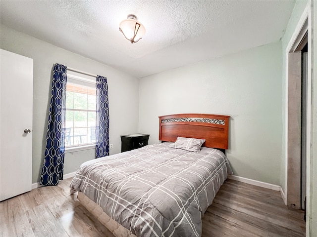 bedroom with hardwood / wood-style floors and a textured ceiling