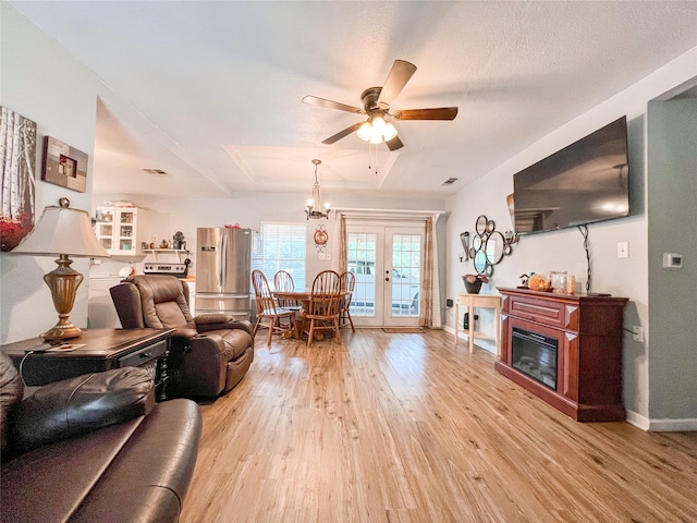 living room featuring visible vents, baseboards, a glass covered fireplace, french doors, and light wood-style floors