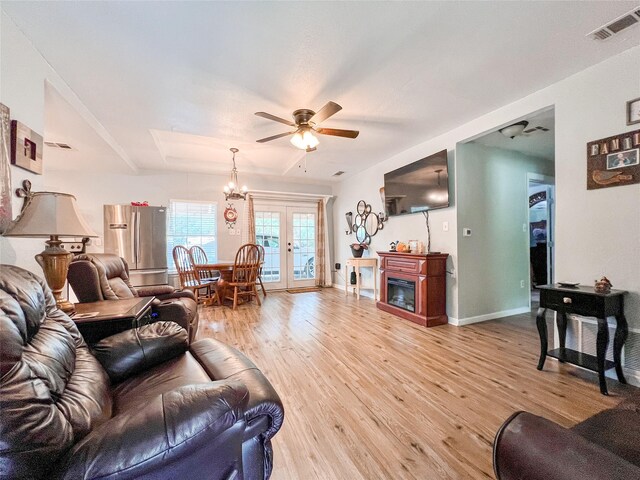 living room featuring light wood-type flooring, ceiling fan, and french doors