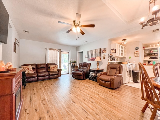 living area featuring visible vents, a ceiling fan, washer / dryer, and light wood-style floors