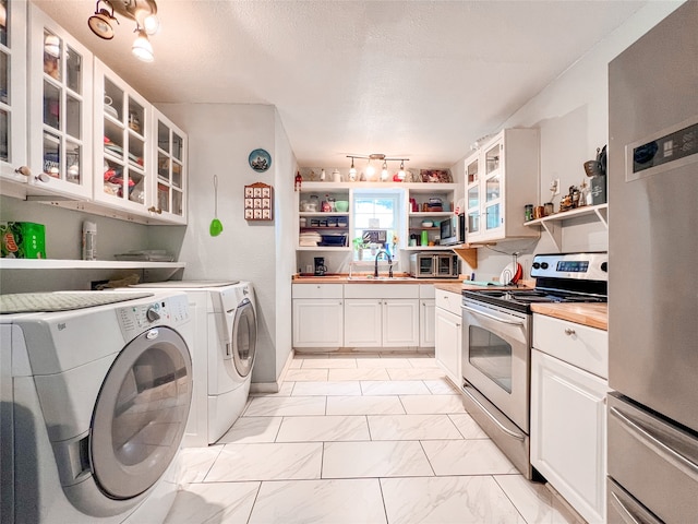 kitchen featuring washer and clothes dryer, white cabinets, appliances with stainless steel finishes, and sink