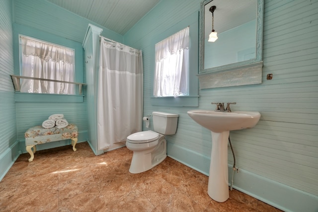 bathroom featuring wood walls, toilet, a shower with curtain, and sink