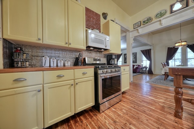 kitchen with cream cabinetry, gas stove, decorative backsplash, and light hardwood / wood-style floors