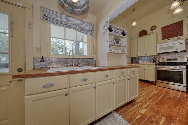 kitchen with decorative light fixtures, sink, decorative backsplash, stainless steel gas stove, and light wood-type flooring