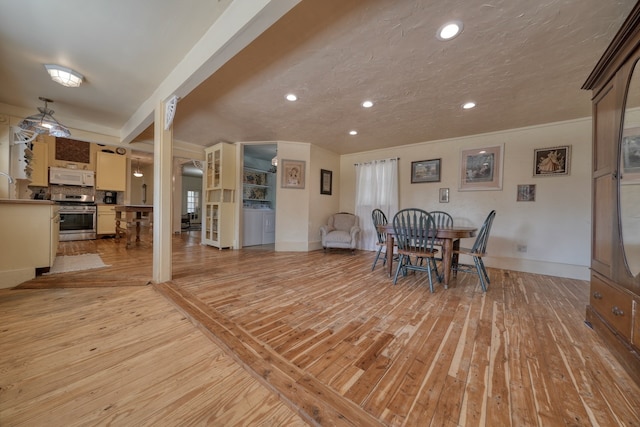 dining area featuring washer and dryer, light hardwood / wood-style flooring, and ceiling fan