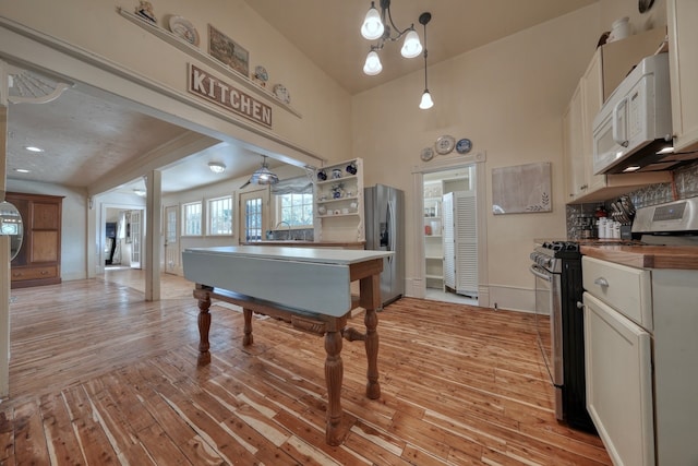 kitchen with light hardwood / wood-style flooring, stainless steel appliances, decorative light fixtures, and white cabinets