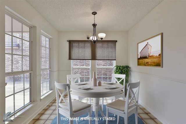 dining space with a wealth of natural light, a notable chandelier, a textured ceiling, and light tile patterned floors