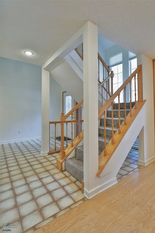 staircase featuring a textured ceiling and wood-type flooring