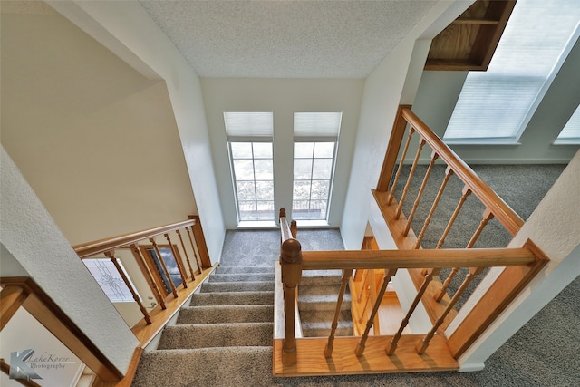 staircase with carpet and a textured ceiling