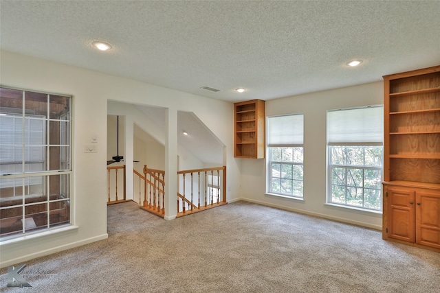 unfurnished living room with light carpet and a textured ceiling