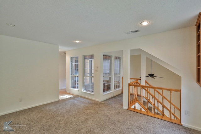 empty room with a textured ceiling, carpet floors, and ceiling fan