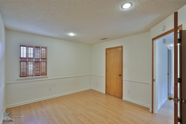 spare room featuring a textured ceiling and light wood-type flooring