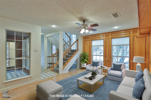 living room featuring ceiling fan, a textured ceiling, and hardwood / wood-style floors