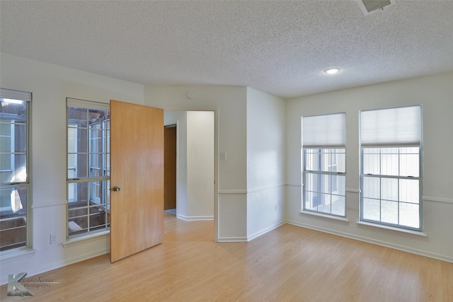 unfurnished room with light hardwood / wood-style floors and a textured ceiling