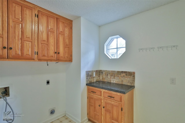 clothes washing area featuring a textured ceiling, electric dryer hookup, washer hookup, and cabinets