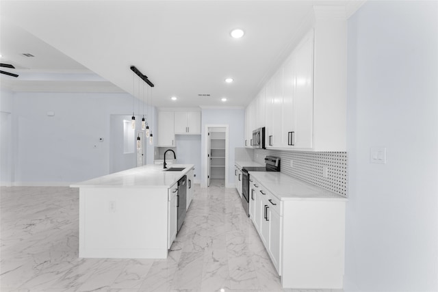 kitchen with decorative light fixtures, appliances with stainless steel finishes, white cabinetry, decorative backsplash, and a center island with sink