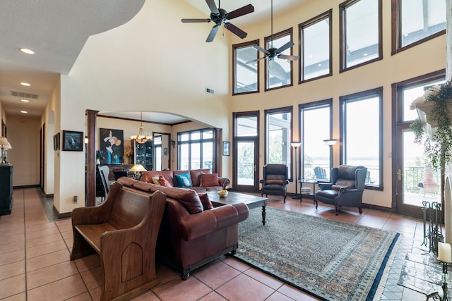 tiled living room with a wealth of natural light, a high ceiling, ceiling fan with notable chandelier, and a textured ceiling