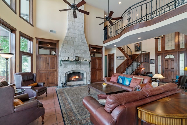 living room featuring a high ceiling, light tile patterned floors, ceiling fan, and a fireplace