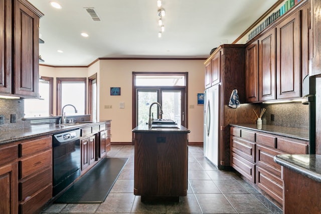 kitchen with black dishwasher, tasteful backsplash, stainless steel fridge, and an island with sink