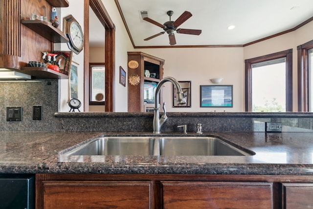 kitchen with ceiling fan, dark stone countertops, ornamental molding, and sink