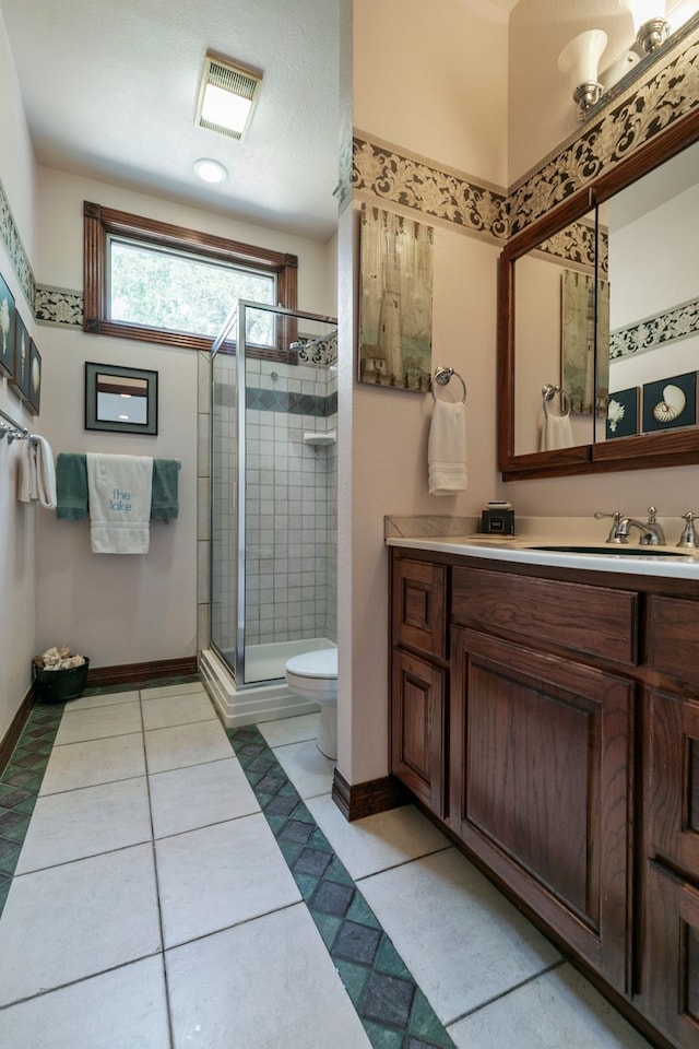 bathroom featuring vanity, toilet, walk in shower, and tile patterned floors