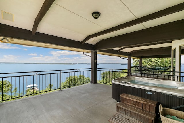 view of patio / terrace with a hot tub and a water view