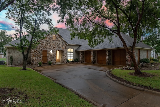 view of front of property featuring a lawn, a garage, and central AC