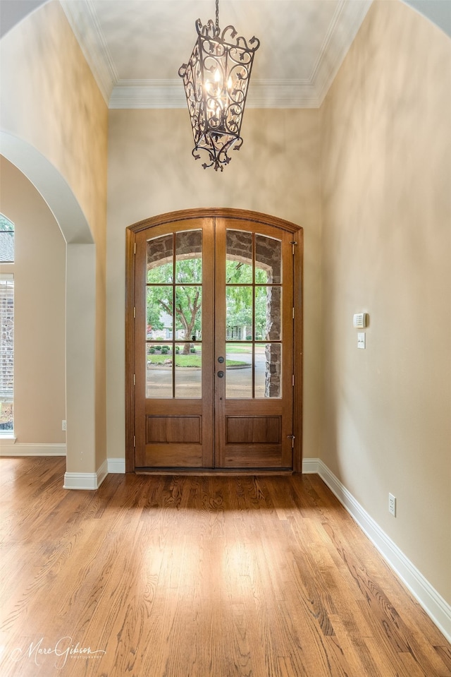 foyer with ornamental molding, a chandelier, and hardwood / wood-style floors