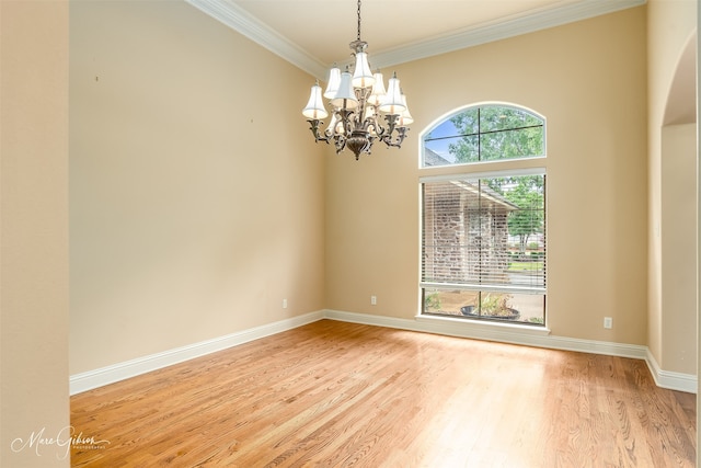 empty room featuring light wood-type flooring, crown molding, and a chandelier