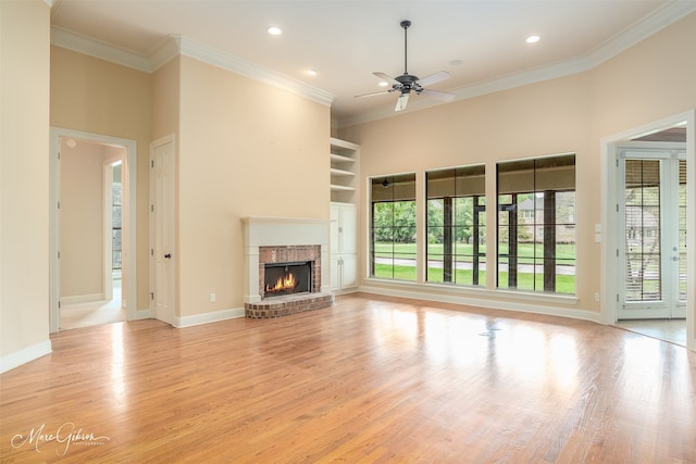 unfurnished living room with light hardwood / wood-style flooring, ceiling fan, ornamental molding, and a brick fireplace