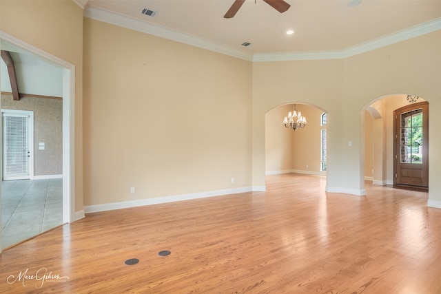 empty room with ceiling fan with notable chandelier, light wood-type flooring, and crown molding