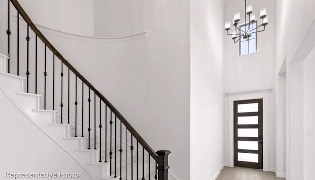 entryway with stairs, a high ceiling, baseboards, and a notable chandelier