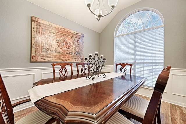 dining space with light wood-type flooring, lofted ceiling, and an inviting chandelier