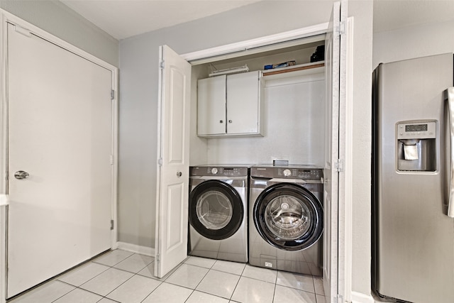 laundry room featuring light tile patterned floors, cabinets, and washer and clothes dryer