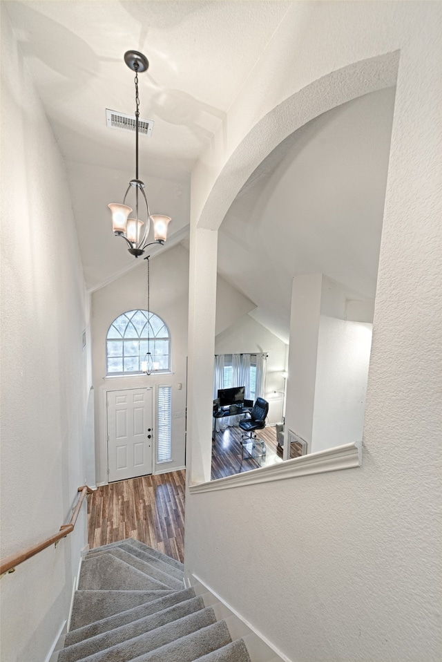 foyer with lofted ceiling, hardwood / wood-style floors, and a notable chandelier