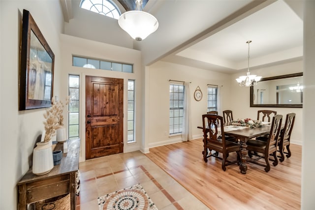 entryway featuring plenty of natural light, a chandelier, light hardwood / wood-style flooring, and a raised ceiling