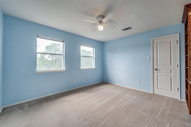 spare room with a textured ceiling, ceiling fan, and carpet floors