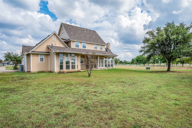 rear view of house with a yard, a sunroom, and central AC