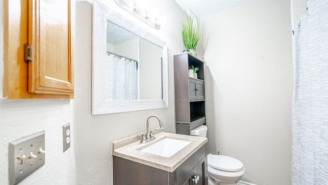 bathroom featuring toilet, a textured ceiling, and vanity