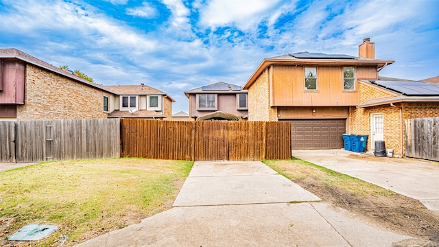 view of front of home featuring a front yard, a garage, and solar panels